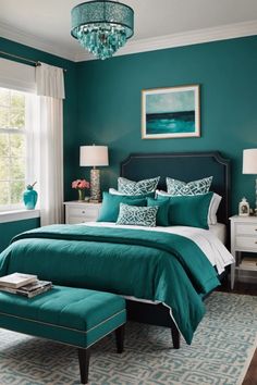 a bedroom with teal colored walls and white furniture, including a large bed in the center