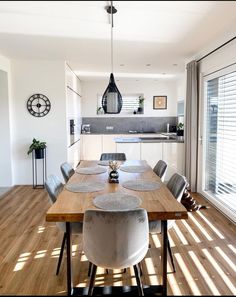 a dining room table with chairs and a clock on the wall