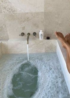 a person's feet in a bathtub filled with blue water and soaps