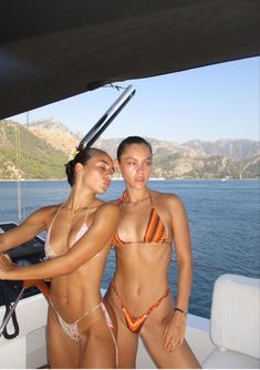 two beautiful women in bikinis standing on a boat