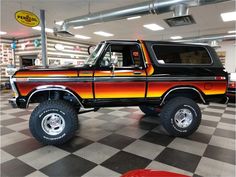 an orange and black truck is parked in a showroom with checkered flooring