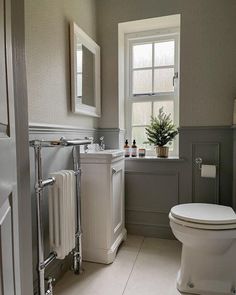 a white toilet sitting next to a window in a bathroom