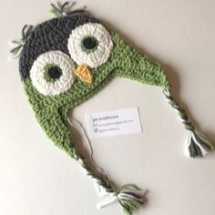 a knitted owl hat sitting on top of a white table next to a tag