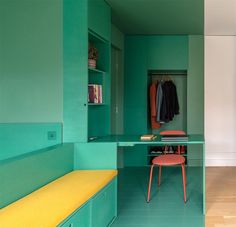 a room with green walls and a yellow bench in the center, next to a closet