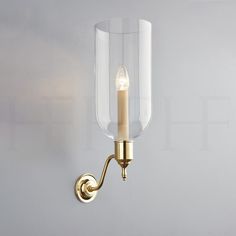 a wall light with a candle in the middle and a clear glass shade on it