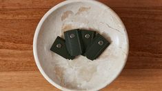 three green leather key fobs in a white bowl