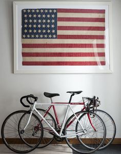 two bikes are parked in front of an american flag hanging on the wall behind them