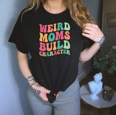 Weird Moms Build Character Shirt, Funny Mom Shirt, Cool Mom Shirt, Weird Mom Shirt, Awkward Mama Shirt, Groovy Mama Shirt, Strange Mom Shirt Ordering Process for our valued customers ~ Please follow all steps to place an order. ~ Please select the hoodie type and size. ~ Please select color of the hoodie from drop down options. ~ If you want to purchase more than 1 , add current item to your cart and then you can click back, add more items for each product. ~ Once all your desired items , you ca Weird Moms Build Character Shirt, Trendy Black Shirt With Funny Text, Black Top With Funny Text For Spring, Trendy Long Sleeve Tops With Funny Text, Black Spring Top With Funny Text, Spring Black Top With Funny Text, Trendy Multicolor Shirt With Letter Print, Trendy Multicolor Letter Print Shirt, Fun Multicolor Tops With Funny Text