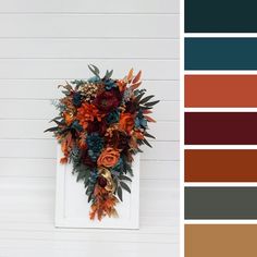 an arrangement of flowers and foliage on a white wall