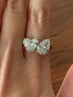 a woman's hand with two pear shaped diamond engagement rings on top of her finger