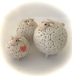 three ceramic sheep standing next to each other on a white surface with spiral designs around them