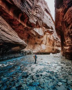 a man standing in the middle of a river surrounded by rocks and water canyons