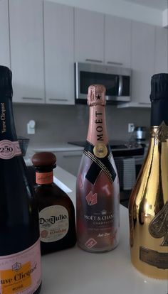 three bottles of wine sitting on top of a counter next to an oven and microwave