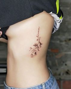 a woman's stomach with a flower tattoo on her side and the lower part of her body