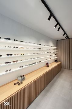 an eyeglass store with rows of glasses on the wall and wooden shelves in front of them