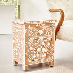 an ornate wooden cabinet sitting next to a white chair