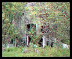 an old abandoned building surrounded by trees in the woods with red and blue 3d glasses