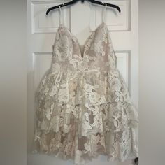 a white dress hanging on a door with a hanger in front of it that has lace over the top