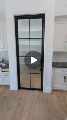 an open glass door in a kitchen with white cabinets and wood flooring on the side