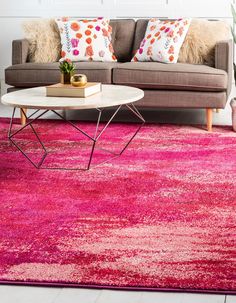 a living room with a couch, coffee table and pink rug