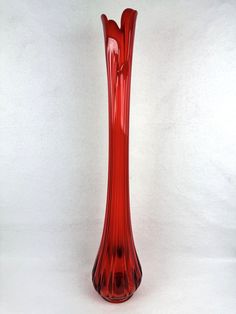 a red glass vase sitting on top of a white table