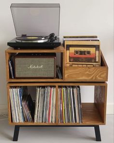 an old record player is sitting on top of a shelf with records and cassettes