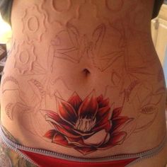 a woman's stomach with tattoos on it and an image of a flower in the center