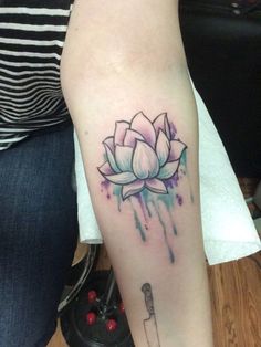 a woman's arm with a watercolor lotus tattoo on it