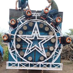 two men on top of a blue and white truck with an upside down star decoration