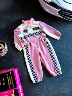 a baby's pink and white outfit next to a car