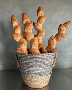 a basket filled with croissants sitting on top of a wooden table next to a gray wall