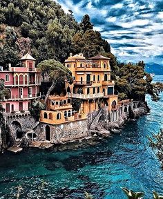 an aerial view of a house on the edge of a cliff by the ocean with trees surrounding it