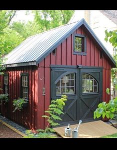 a small red shed sitting in the middle of some trees