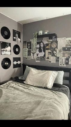 a bed sitting in a bedroom next to a wall with pictures on it and vinyl records