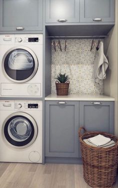 a washer and dryer in a small laundry room with grey cabinets, white counter tops, and wooden flooring