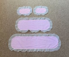 three pieces of pink and white paper with ruffles on them sitting on the floor