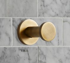 a close up of a toilet paper holder on a marble tile wall in a bathroom