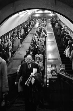 an old black and white photo of people riding on escalators in a subway