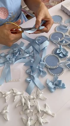 a woman cutting ribbon with scissors on a table covered in blue and white decorations,