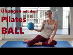 a woman sitting on a mat with a ball in her hand and the words pilates ball