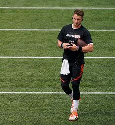 a man holding a football on top of a field with grass and white lines in the background