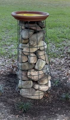 a bird bath made out of rocks in the grass