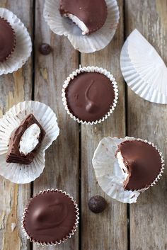 chocolate cupcakes with white frosting and one cut in half on a wooden table