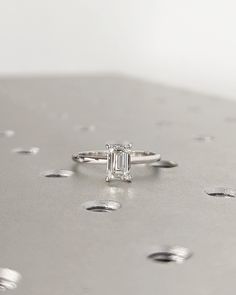 a diamond ring sitting on top of a silver surface with drops of water around it