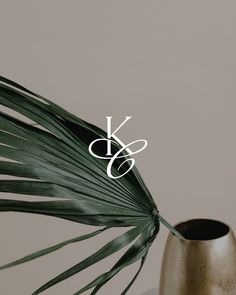 a gold vase sitting on top of a table next to a palm leaf