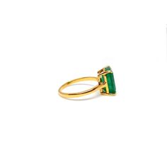 a gold ring with an emerald stone in the middle and a diamond on the side