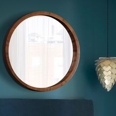 a round mirror hanging on the wall next to a bed