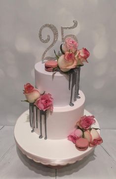 a three tiered cake with pink flowers on top and the number twenty five in silver