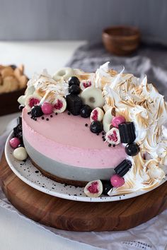 a cake with white frosting and toppings on a wooden platter next to cookies