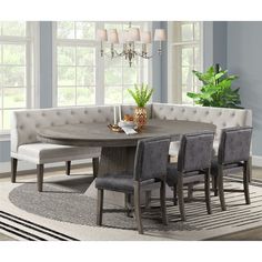 a dining room table with four chairs and a bench in front of the window, next to a potted plant